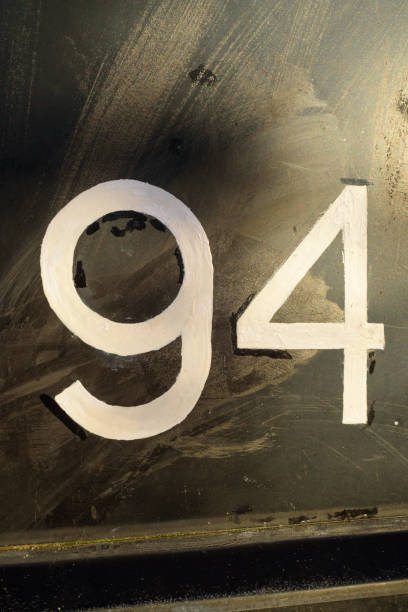 Number 94  painted on black metal surface
