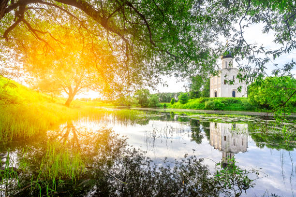 Church of Intercession upon Nerl River 12th century. (Bogolyubovo, Vladimir region, Golden Ring of Russia) A warm summer evening. historical and cultural heritage of Russia. Landscape with a reflection of the church in the foliage. The sun's glare
