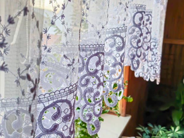 istock Delicate lace curtain with floral patterns softly filtering sunlight, enhancing the interior ambiance of a home. 2184996608