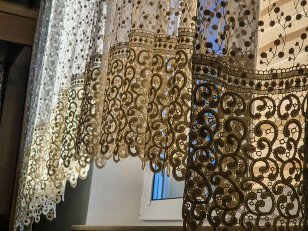 istock Elegant lace curtain with intricate patterns, softly illuminated by natural light through a window, creating a serene and inviting atmosphere. 2184996875