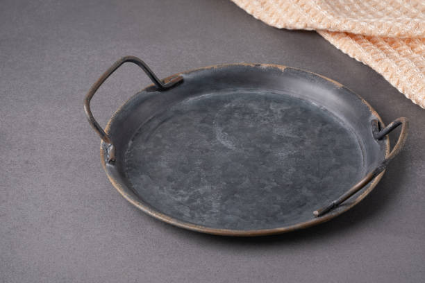 istock A vintage round metal tray with handles placed on a textured surface next to a woven cloth background showcasing rustic charm 2184997039