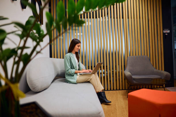 istock Professional Woman Smiling While Using Laptop in Office Lounge 2184997497