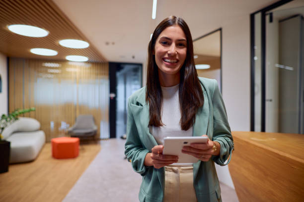 istock Confident Businesswoman Smiling With Tablet in Modern Office Setting 2184997604