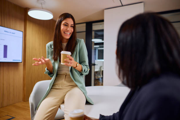 istock Businesswomen Engaged in Friendly Conversation Over Coffee in Office 2184997788