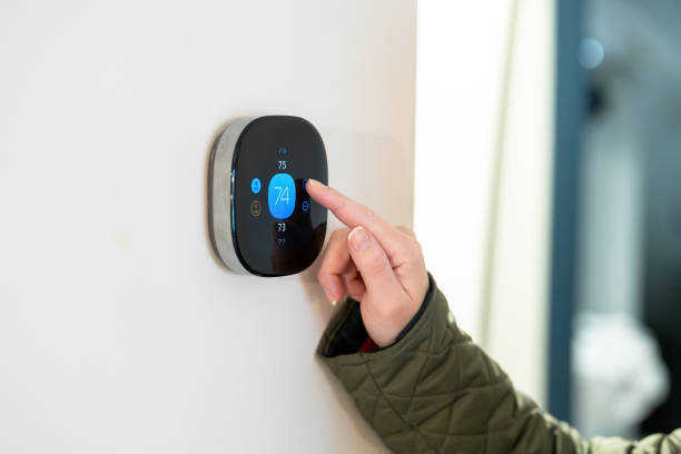 istock woman adjusting temperature on digital thermostat 2185000069
