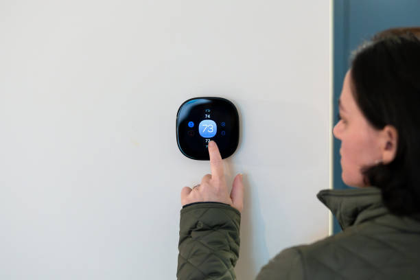 istock woman adjusting temperature on digital thermostat 2185000071