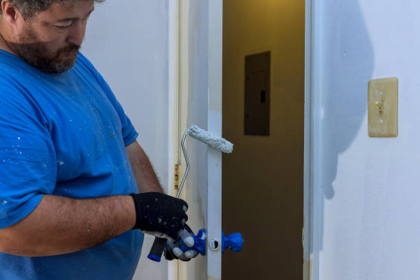 istock Craftsman carefully paints door frame with roller in home interior during home improvement 2185000555