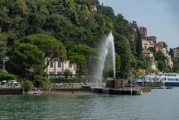 Omegna, Italy - October 17, 2021: Spray from fountains on the neck of lake Orta at Omegna catches the sunlight