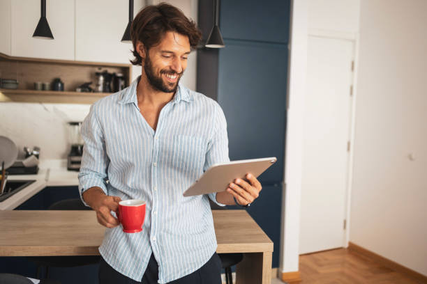 istock Man standing in the kitchen and reading the news on digital tablet 2185006057