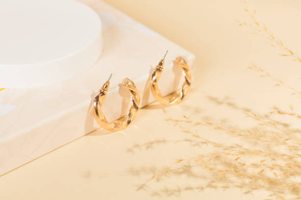 Golden earrings with decor on color background