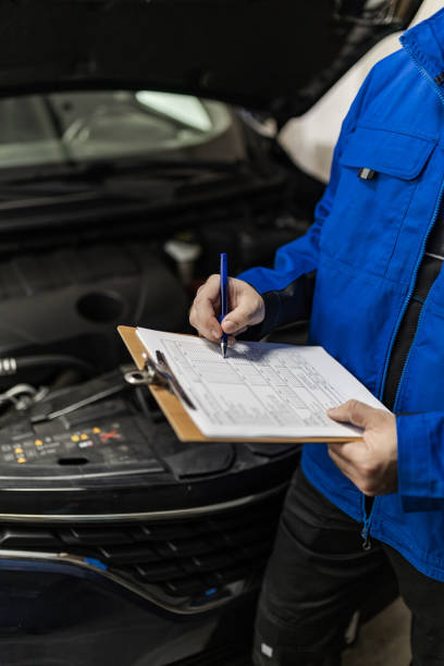 istock Mechanic performing vehicle inspection in a garage while taking notes on a clipboard during daylight hours 2185009246