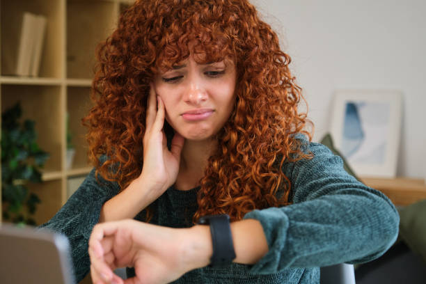 istock Young woman suffering from toothache while working from home and checking time on smartwatch 2185009508