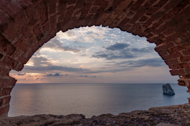 View through old brick windows to the sea at sunset