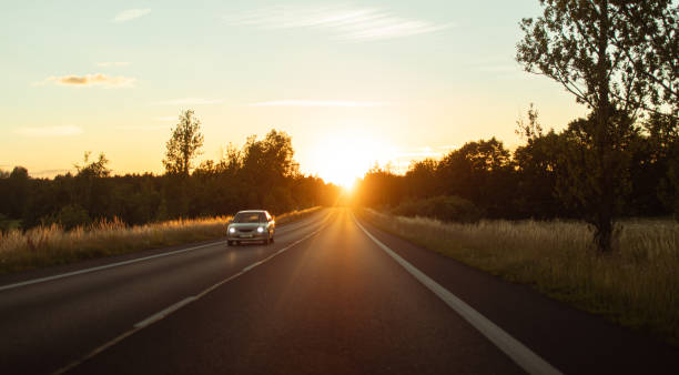 istock Car driving down country road at sunset. 2185010367