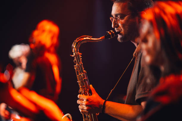 istock Saxophonist playing sax on stage with band in background 2185015635