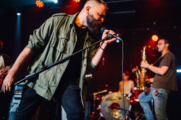 istock Singer performing with passion on stage with band 2185015695