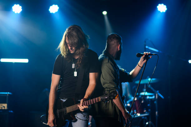 istock Guitarist and singer performing live on stage under blue lights 2185015763