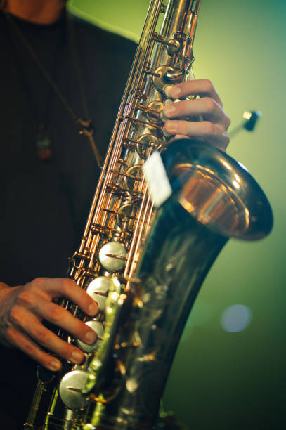istock Saxophonist playing saxophone on stage with green background 2185015800