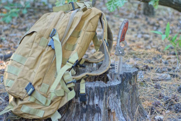istock one brown army backpack and a folding knife standing on a earth 2185019579