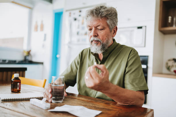 istock Senior man medicating himself with medicine at home 2185020171