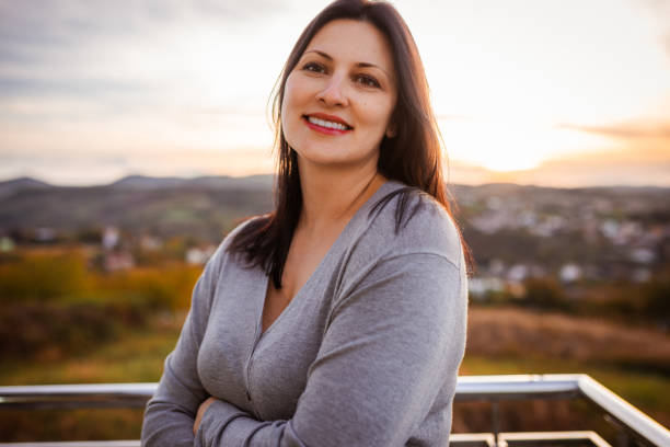 istock Smiling Woman Enjoying Sunset Outdoors With Scenic View 2185024835