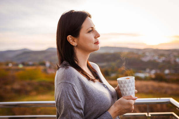 istock Woman Enjoying Hot Beverage Outdoors at Sunset 2185024839