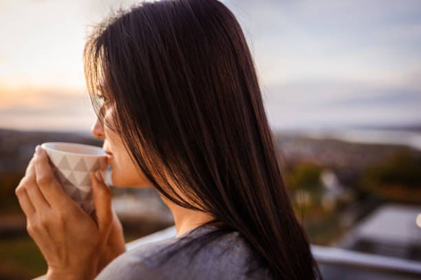 istock Woman Enjoying Hot Beverage Outdoors at Sunset 2185024841