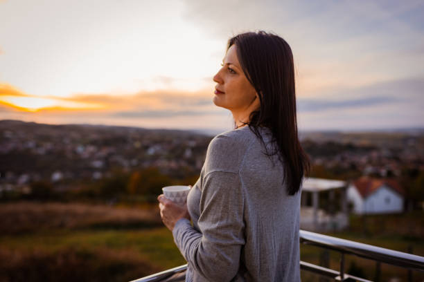 istock Woman Enjoying Hot Beverage Outdoors at Sunset 2185024844