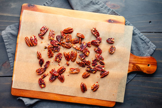 Toasted pecans on unbleached baking paper lined wooden cutting board