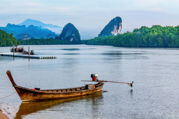 Longtail Boat on river. Rocks, moutains, forest in the background. stock photo