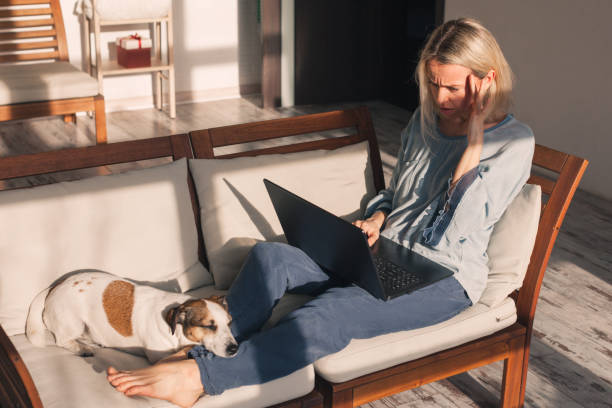 istock Frustrated sad middle aged woman feeling tired worried about problem sitting on sofa with laptop 2185035085