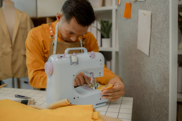 istock a fashion designer is working in his studio doing what he loves, he does many things such as using a sewing machine to sew a dress, choosing the fabric to use to make the dress 2185040092
