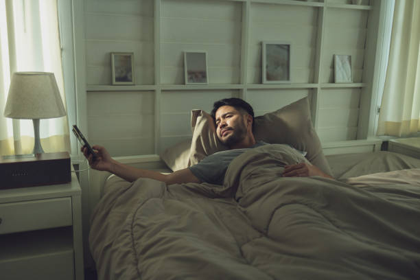 istock Man Reaching for Phone in Bed in Cozy, Softly Lit Bedroom 2185041308