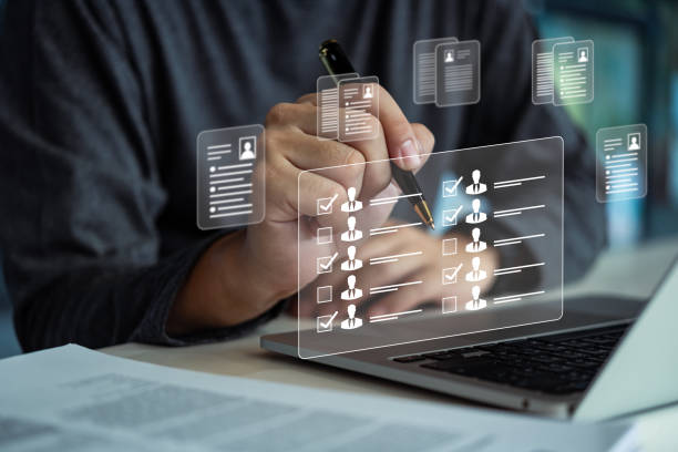 istock Hand reviewing and checking profiles using a holographic interface on a laptop. Highlights recruitment, team selection, and HR processes. 2185057770