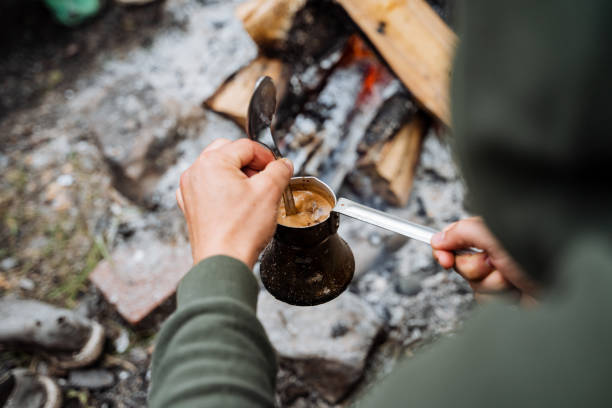 istock Imagine someone making coffee by a crackling outdoor fire, creating a cozy atmosphere. This scene exudes relaxation and warmth, immersed in the tranquil beauty of nature 2185068754