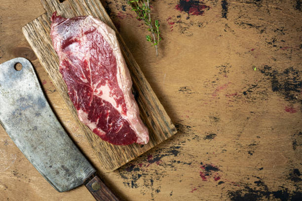 istock A raw meat steak is placed on a wooden cutting board alongside a sharp cleaver and fresh herbs, highlighting the preparation for cooking meat 2185075908