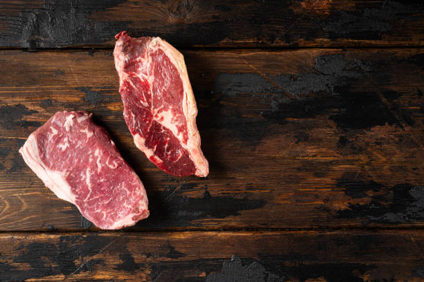 istock Two raw beef steaks lie on a rustic wooden table, displaying rich marbling and a vibrant red color, perfect for preparing a delicious meal at home 2185075961