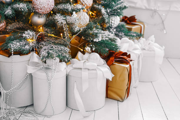 istock Wrapped holiday gift boxes under beautifully decorated Christmas tree with white and gold ornaments 2185078289