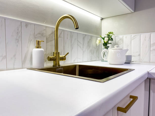 istock In a welldesigned kitchen, there is a lovely kitchen sink that features a luxurious gold faucet accompanied by a convenient soap dispenser elegantly placed on the countertop 2185080473