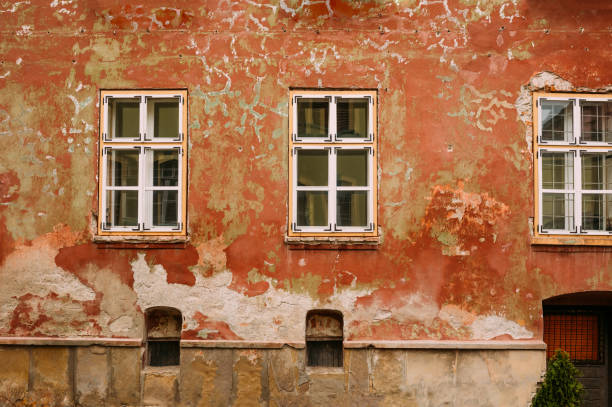 An old Weathered Wall adorned with Windows and featuring Peeling Paint that captures history