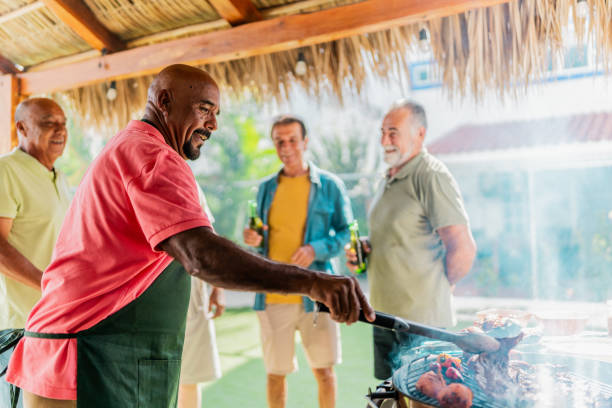 istock Senior man doing barbecue with friends at home 2185083121