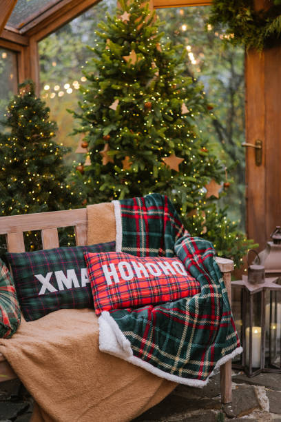 istock Cozy Christmas interior with a bench, plaid pillows, decorated Christmas trees, lanterns, and a warm festive atmosphere in a glass greenhouse. 2185088196
