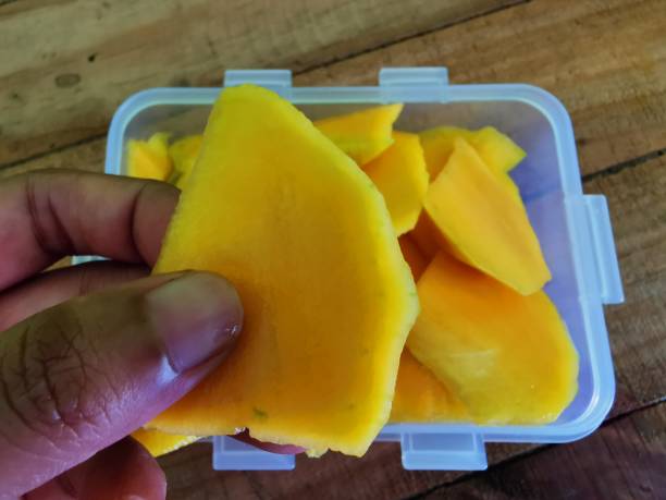 istock a hand holding a slice of manggo 2185093168