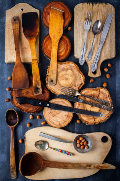 istock Old wooden cutting boards, tree trunk slices, nuts and kitchen utensils on black chalkboard 2185093239