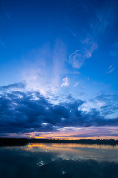 A breathtaking sunset is casting vibrant and stunning colors over the calm waters and a dramatic sky above