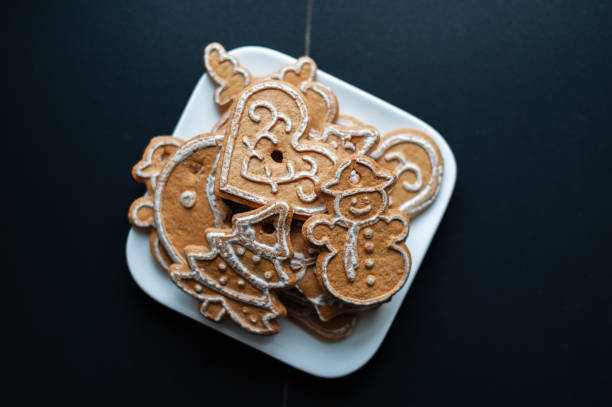 A plate of Christmas cookies with a tree and snowman on it. The cookies are piled on top of each other