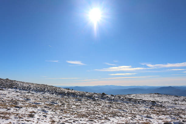 istock Snow-covered terrain, with mountains in the background and a clear blue sky with a shining sun 2185097989