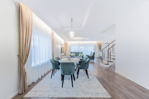 istock Scandinavian Style Cozy Modern Open Bright Kitchen Home Interior. Dining Table and Furniture in Background. Candles on the Table. Cabinets. Carpet, Windows and Curtains. Living Room in Background 2185099996