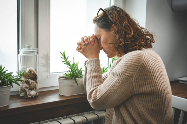 istock sad woman sitting by the window next to the radiator 2185100258