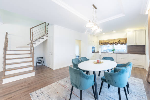 istock Scandinavian Style Cozy Modern Open Bright Kitchen Home Interior. Dining Table and Furniture in Background. Candles on the Table. Cabinets. Carpet, Windows and Curtains. Upstairs 2185100430